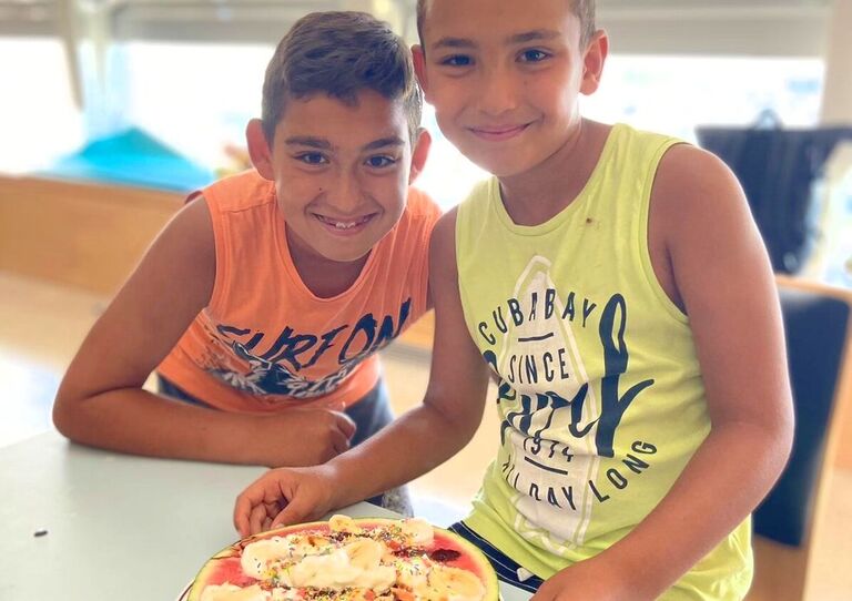 Zwei Buben mit einer selbst gemachten Melonen-Pizza.