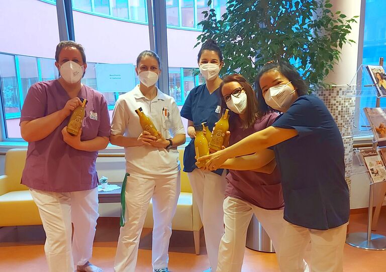 Mitarbeiter*innen stehen für ein Gruppenbild zusammen und halten jeweils eine Flasche Innocent Smoothie hoch.