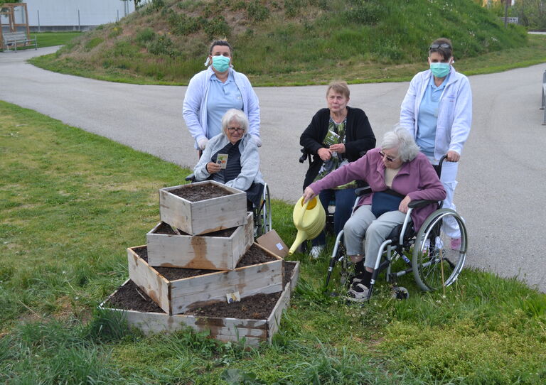 Die Bewohnerinnen gießen gemeinsam mit den Mitarbeiterinnen die neue Gemüsepyramide.