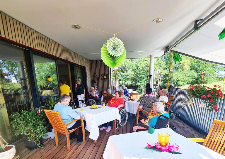 Eine Aufnahme vom schön dekorierten Balkon und den Bewohner*innen, die darauf feiern.