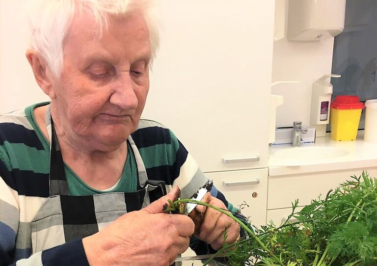 Eine Bewohnerin putzt die Karotten.