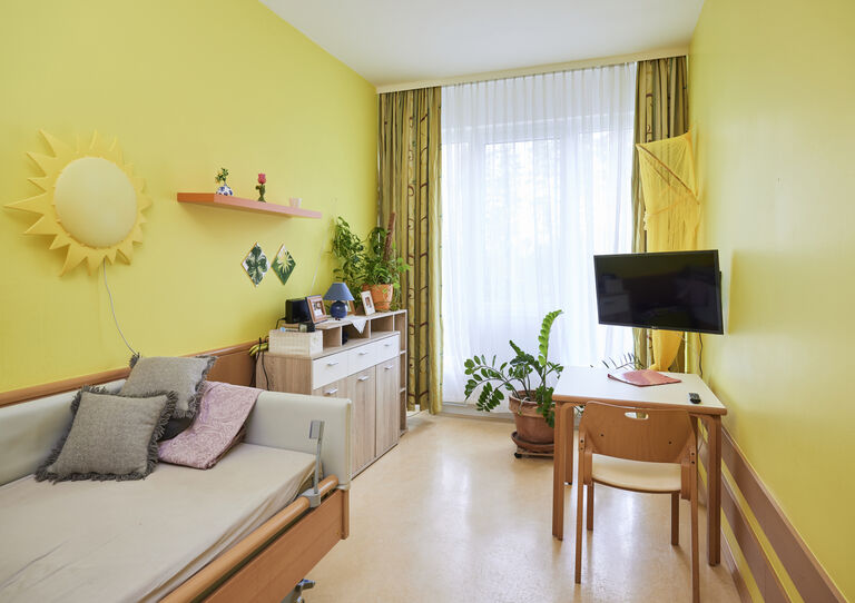 Kund*innen-Zimmer mit gelber Wandfarbe in der WG 1 Clementinum