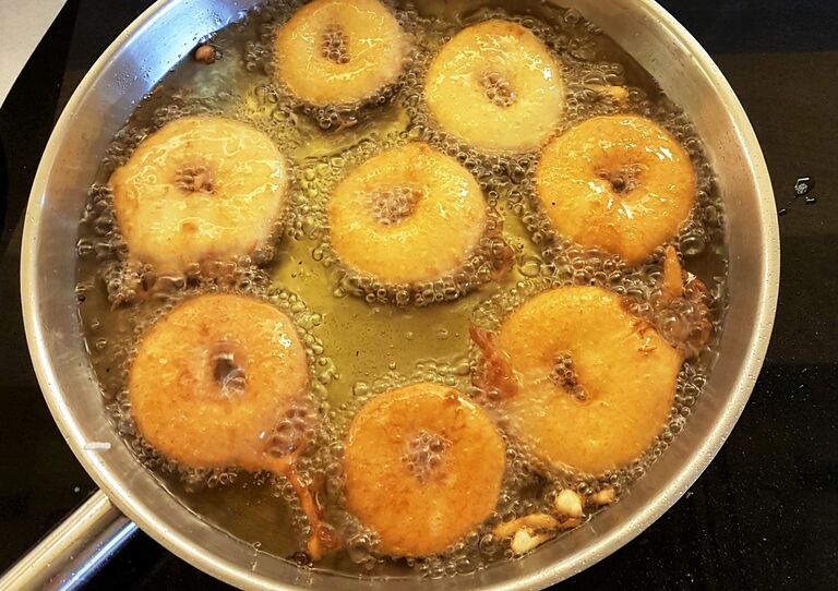 Die Apfelscheiben braten in einer Pfanne mit Öl.