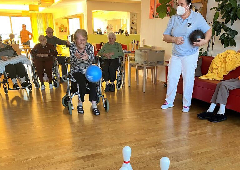 Eine Bewohnerin landet einen kräftigen Wurf. Betreuerin Marija hält bereits den nächsten Ball bereit.