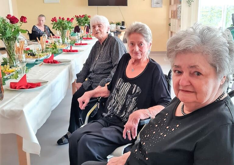 Bewohnerinnen nehmen am Tisch Platz.