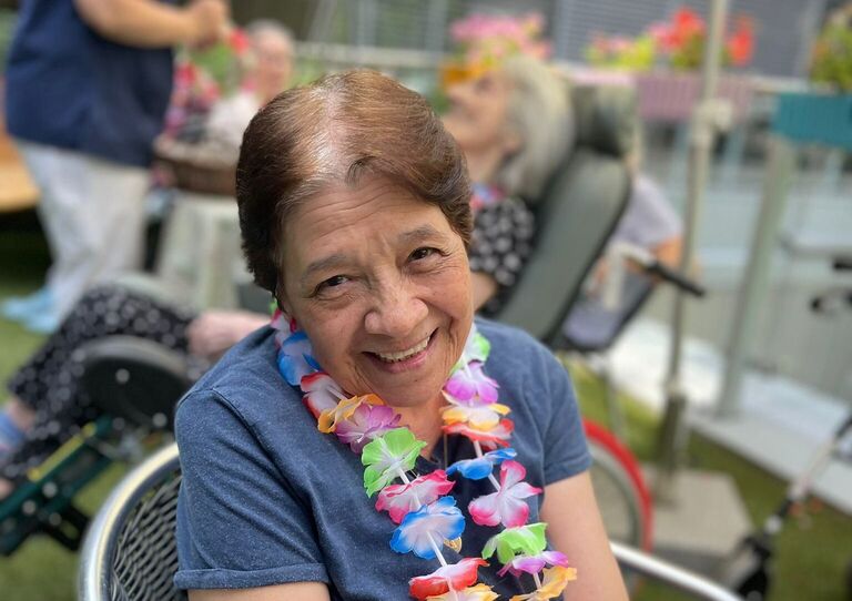 Eine Bewohnerin mit Blumenkette blickt in die Kamera