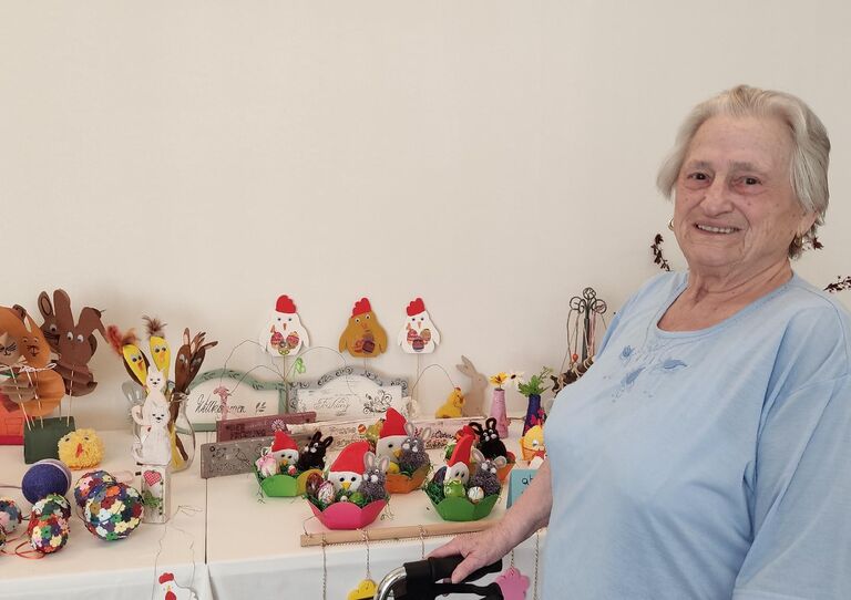 Bewohnerin präsentiert stolz die Osterbasteleien für den Ostermarkt.