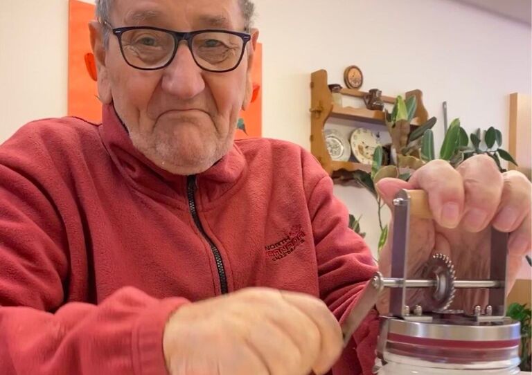 Ein Bewohner schlägt mit einer Handmaschine Schlagobers