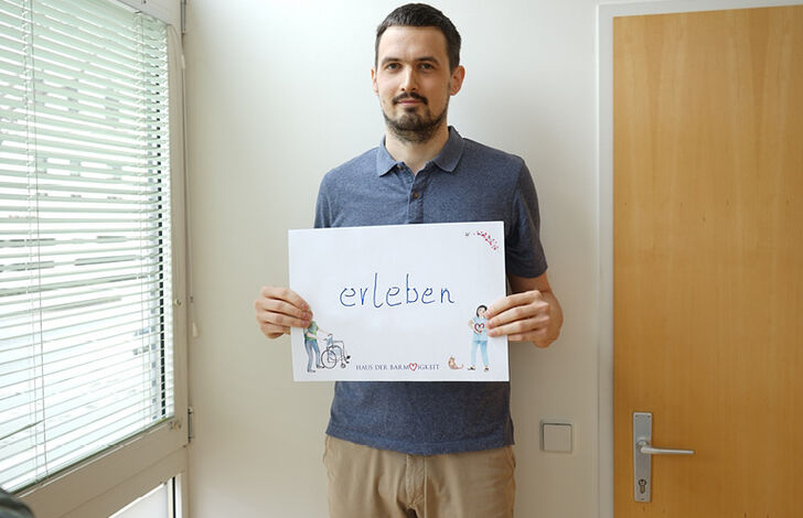 Mitarbeiter hält Schild mit "erleben"