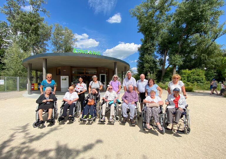 Bewohner*innen und Mitarbeiter*innen stehen für ein Gruppenbild zusammen. Sie besuchen gleich eine Pflanzenausstellung.