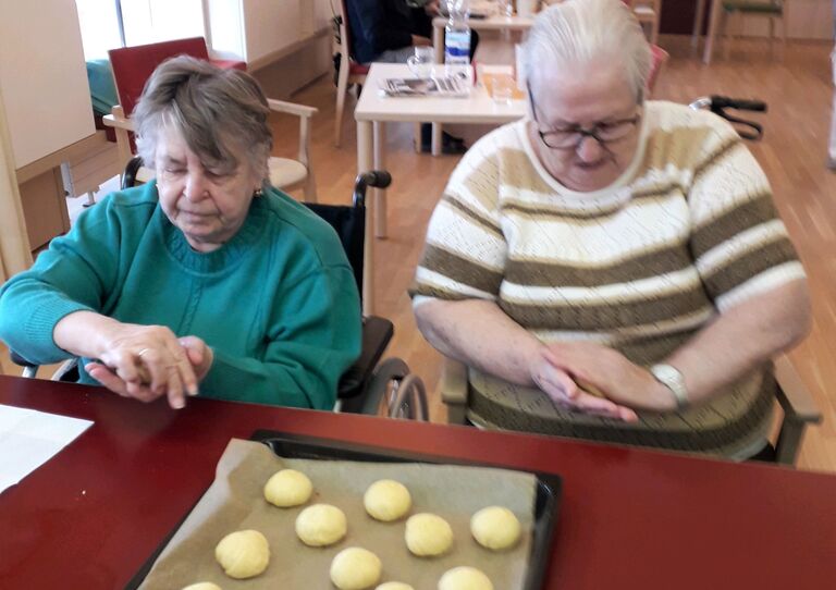 Zwei Bewohnerinnen rollen Krapfenbälle.