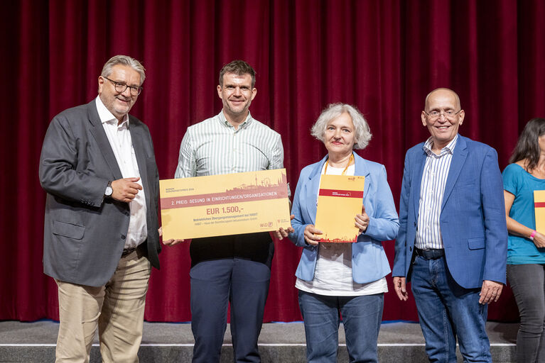 Gruppenbild mit Stadtrat und Projetkteam vor rotem Vorhang mit Urkunde in der Hand.