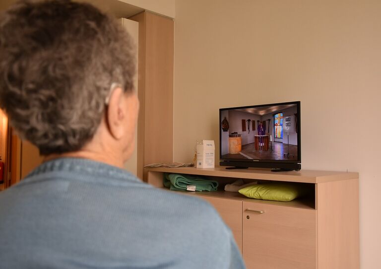 Eine Bewohnerin verfolgt den Gottesdienst über TV in ihrem Zimmer.