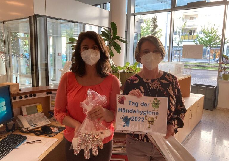 Zwei Kolleg*innen halten Geschenke in die Kamera.