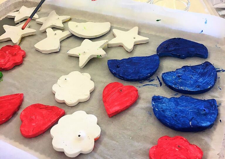 Fertig bemalte und noch zu bemalende Anhänger auf einem Tablett.