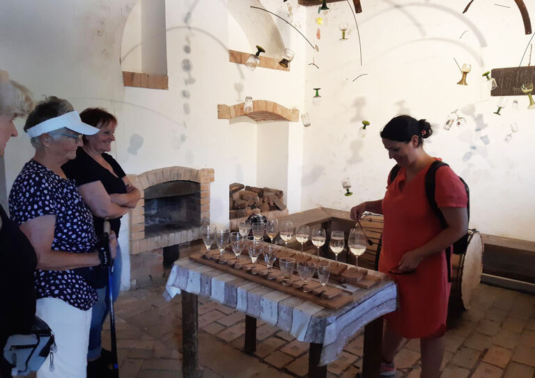 Auf einem Tisch stehen mehrere gefüllte Weingläser und die Mitarbeiter*innen stehen rund herum.