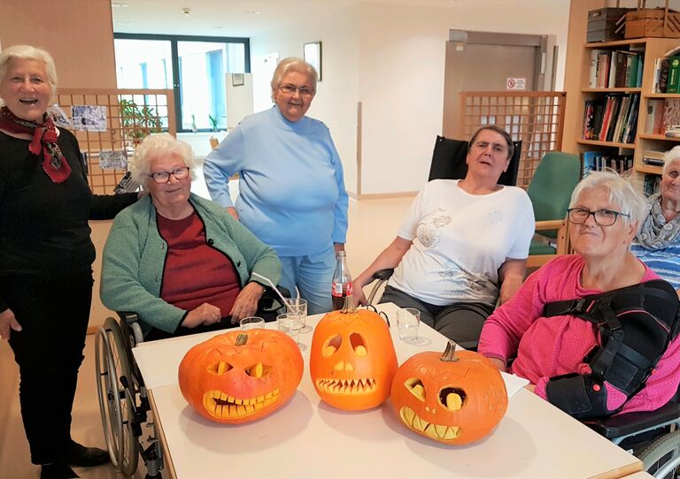 Unsere Bewohnerinnen freuen sich über die gelungenen Kürbisköpfe, die im Vordergrund zu sehen sind.