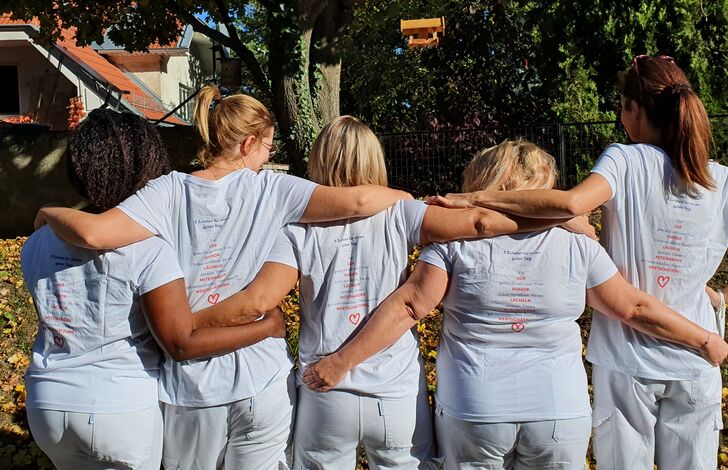 Mitarbeiter*innen stehen von hinten aus zusammen.