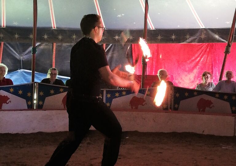 Ein Jongleur jongliert mit brennenden Keulen.