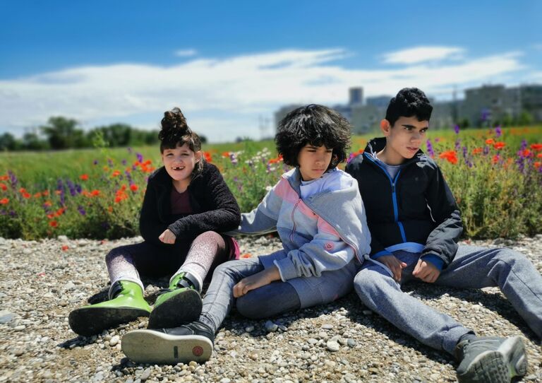 Die Kinder der HABIT Kids WG genießen den Sonnenschein in einer bunten Blumenwiese.