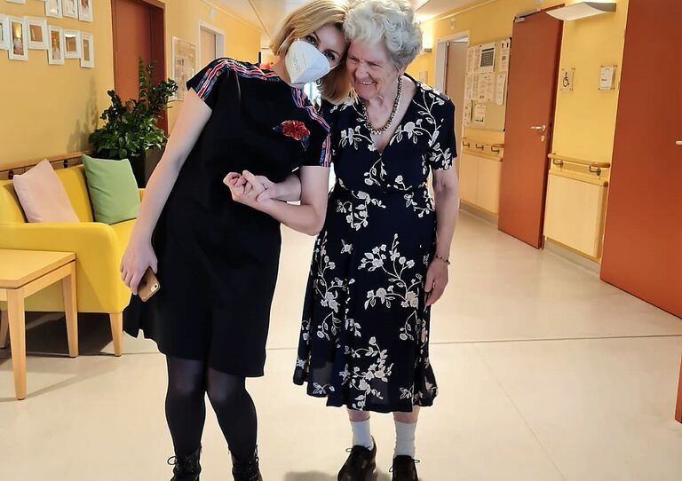 Festlich gekleidete Bewohnerin am Arm einer Mitarbeiterin.
