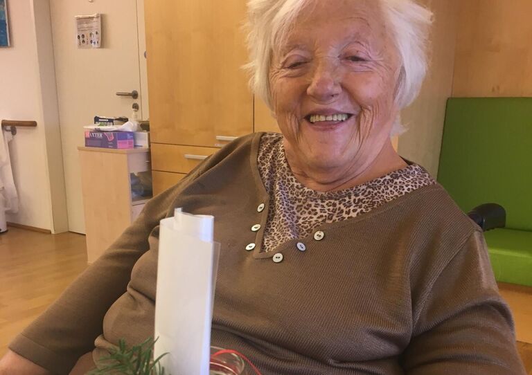 Eine Bewohnerin sitzt am Tisch vor ihr ein Gläschen aus dem Adventkalender. In dem Gläschen ist ein Blatt Papier zusammen gerollt. Darin befindet sich die Geschichte.