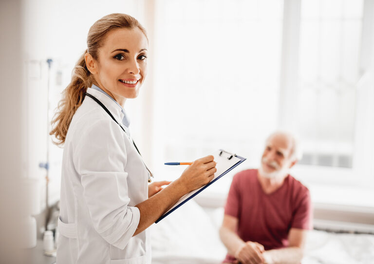 Ärztin macht sich im Gespräch mit Patienten Notizen.