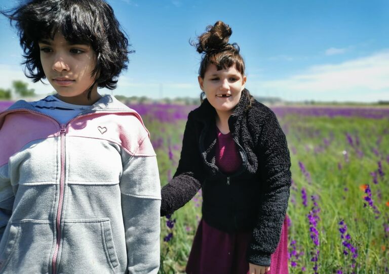 Die Kinder der HABIT Kids WG genießen den Sonnenschein in einer bunten Blumenwiese.