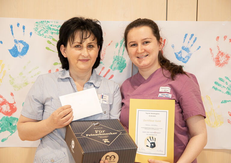 Zwei Kolleginnen halten ihre Preise in die Kamera