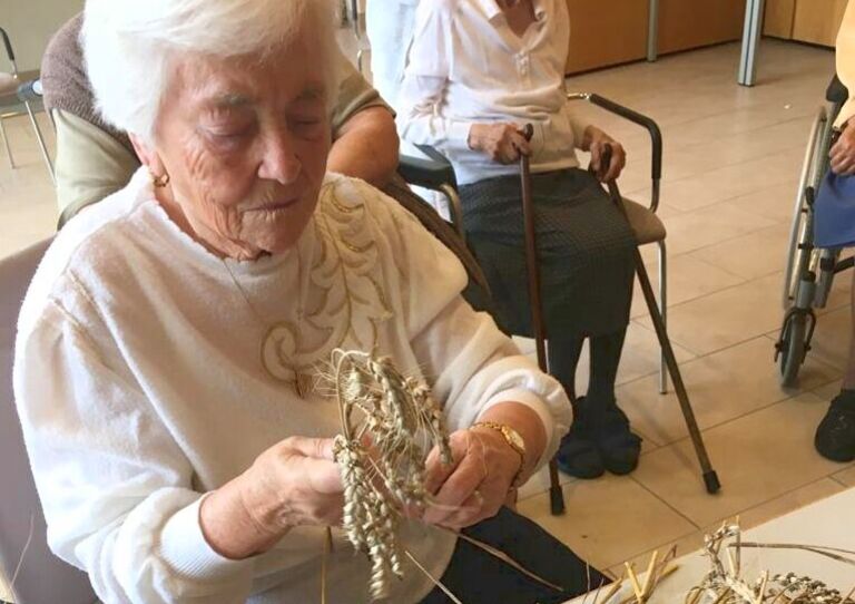 Eine Bewohnerin richtet das Getreide für die Erntedankkrone zurecht.