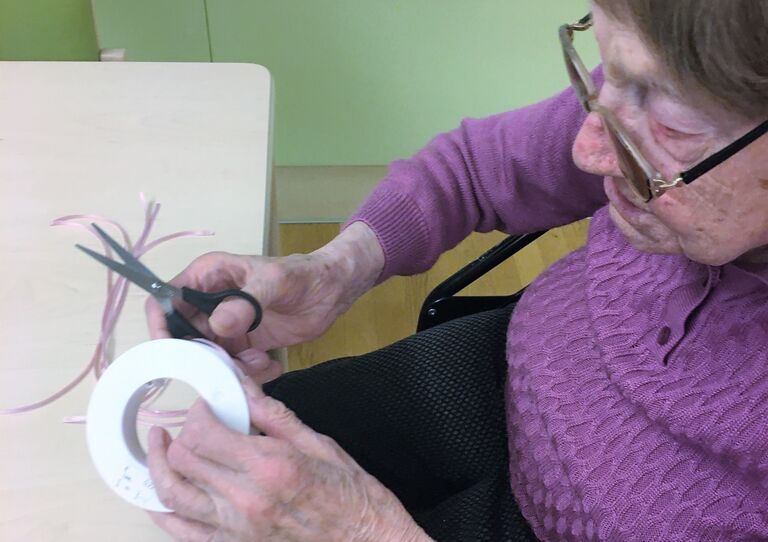 Bewohnerin Katharina bindet einen Palmbuschen.
