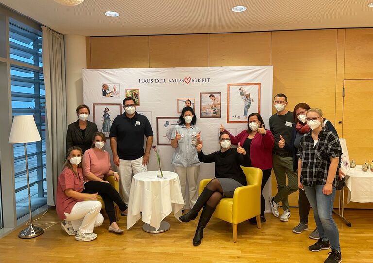 Zehn Mitarbeiter*innen aus dem HB stehen für ein lustiges Gruppenbild zusammen.