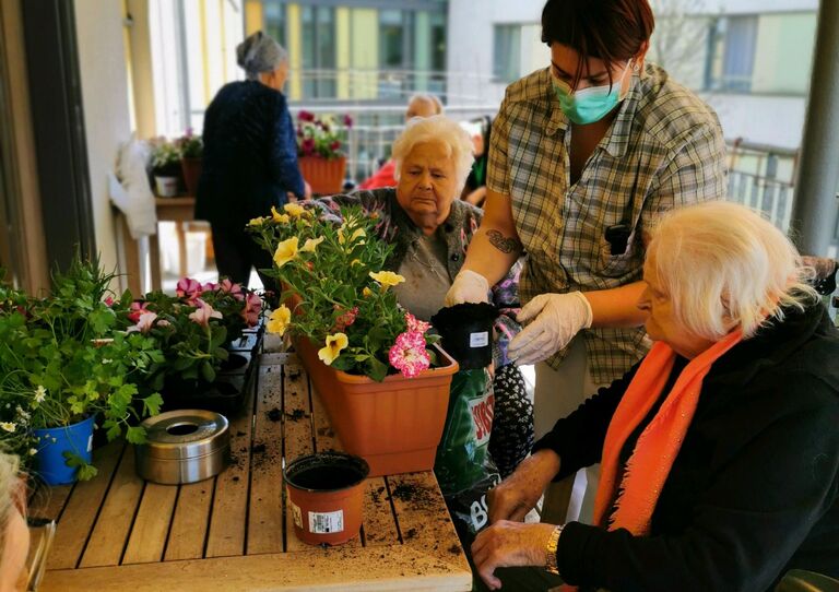 Zu zweit bepflanzen die Bewohnerinnen hier die Kübel.