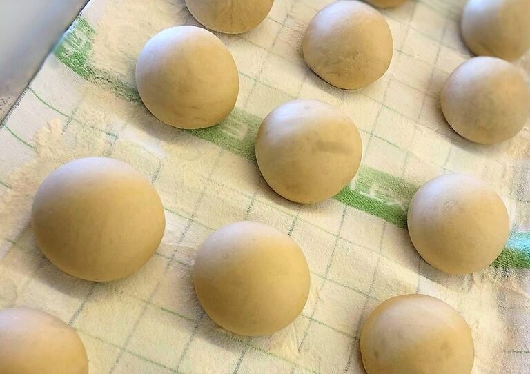 Die gerollten Krapfen-Bälle warten auf einem Blech auf das Herausbacken.