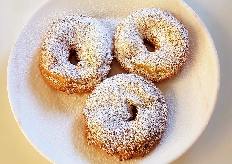 Drei fertige mit Zucker bestreute Apfelringe.