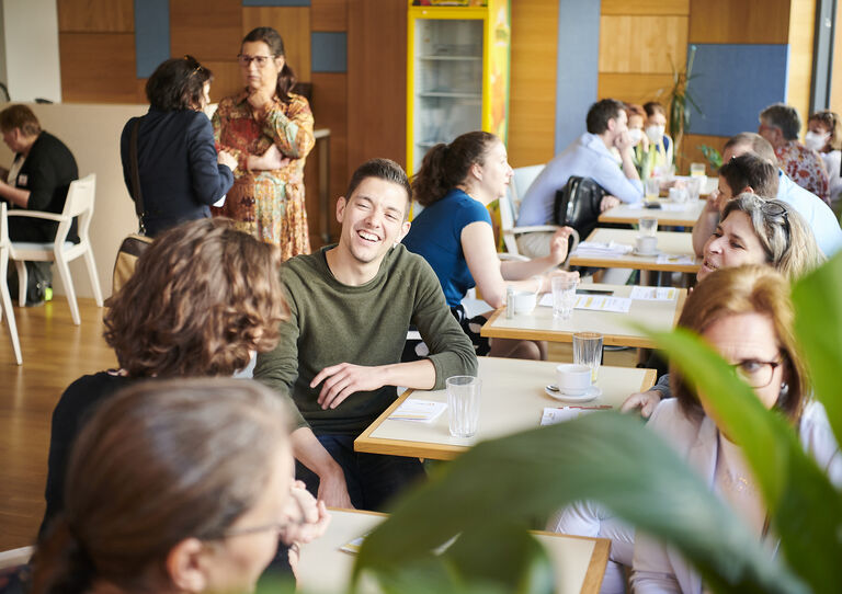 Publikum in der Pause im Bereich der Kantine unterhält sich.