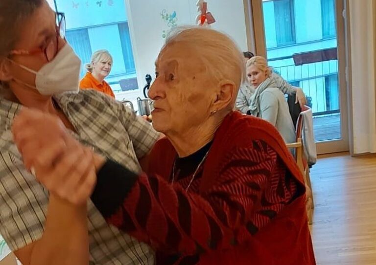 Mitarbeiterin Petra tanzt mit einer Bewohnerin.