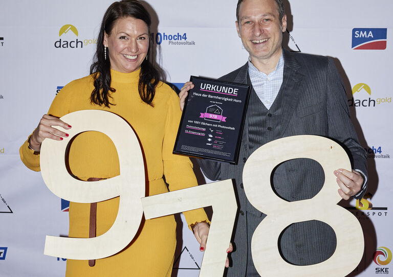 Cornelia Daniel Gründerin Tausendundein Dach und Ralph Alexander Aichinger, die die Zahl 978 hoch halten.