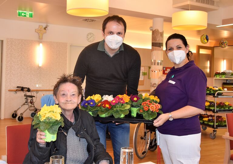 Heimleiter Gregor Kopa und Pflegedienstleiterin Tanja Glander verteilen Blumen an Bewohnerinnen.