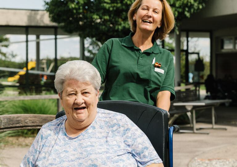 Lachende Bewohnerin und Mitarbeiterin.