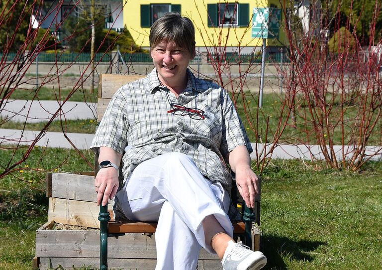 Hausleiterin Sonja Kriz genießt die Sonne auf einer Bank.