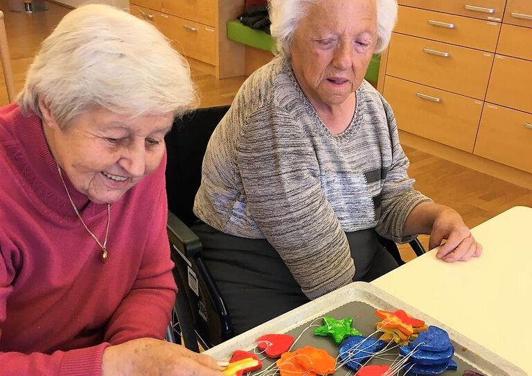 Zwei Bewohnerinnen begutachten die fertigen bunten Kunstwerke.
