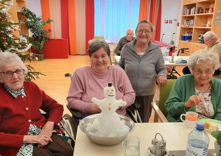 Vier Bewohnerinnen präsentieren einen fertigen Indoor-Schneemann.