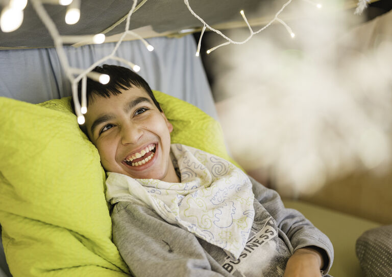 Ein lachendes Kind unter einer Lichterkette.