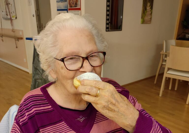 Bewohnerin beißt herzhaft in den Krapfen.