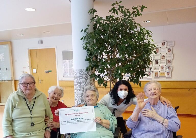 Bewohner*innen im Rollstuhl freuen sich über den eingenommen Betrag, den sie spenden werden.