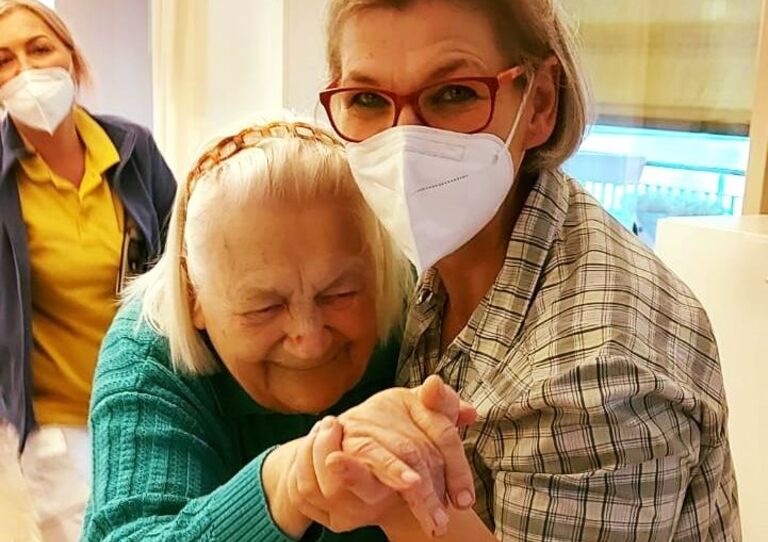 Eine Mitarbeiterin tanzt mit einer Bewohnerin.