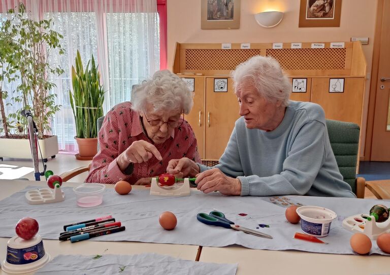 Zwei Bewohner*innen bemalen Ostereier.