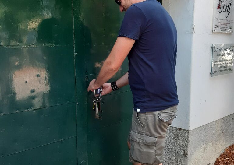 Mitarbeiter öffnet eine Türe zu einem Weinkeller.