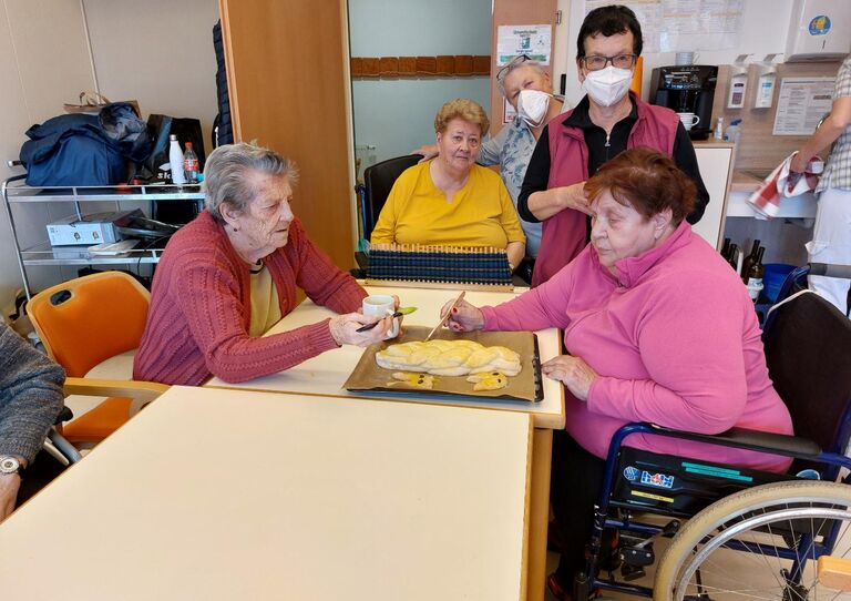 Bewohnerinnen bestreichen einen selbst gebackenen Osterstriezel.
